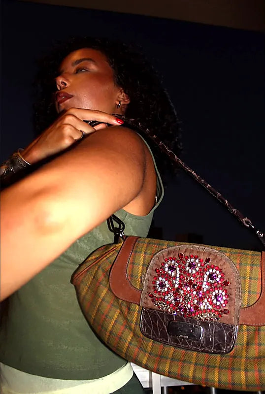 Night flash shot of a crystal-embellished tartan shoulder bag worn over the shoulder
